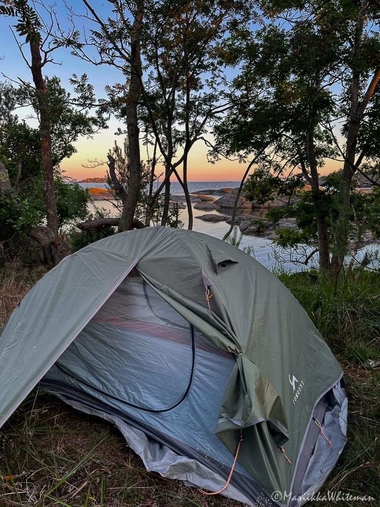 A tent in an island with a sunset on the background. 100 nights out